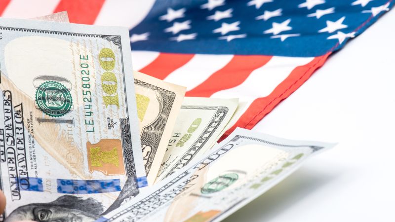 Tiền đô la Mỹ và quốc kỳ Mỹ thể hiện chi phí sinh hoạt tại Mỹ - First Consulting Group